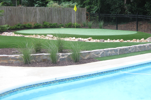small putting green and artificial grass surrounding swimming pool